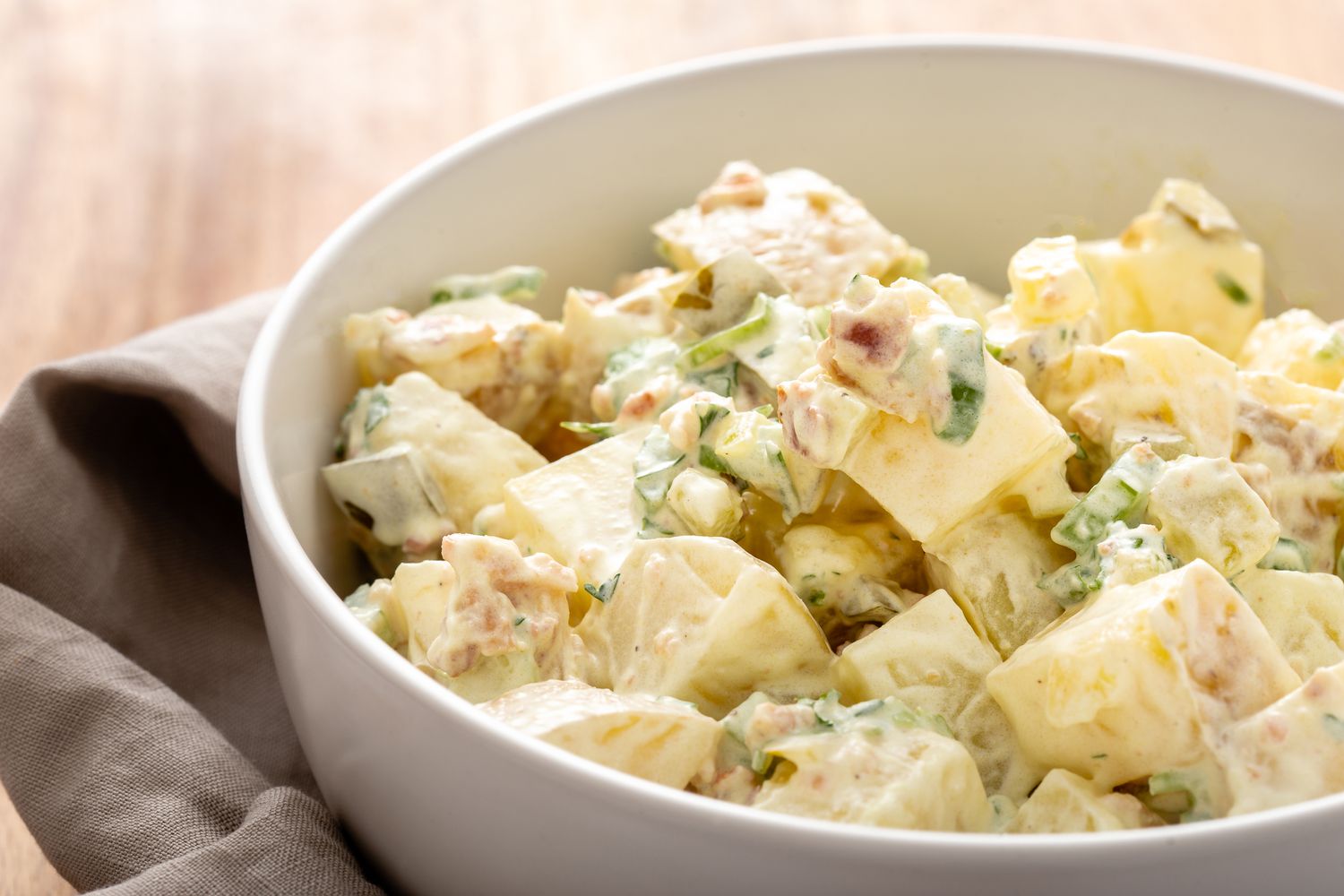 Side view of homemade potato salad in a white bowl.