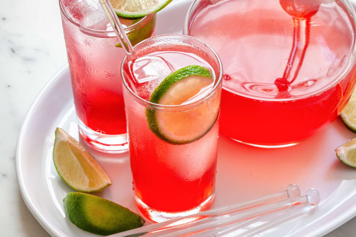 Best ever raspberry lime rickey in two glasses with a pitcher behind it.