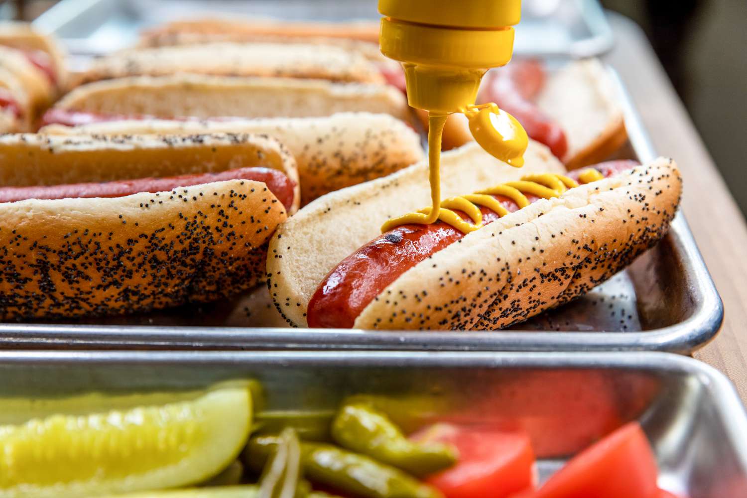 Topping a Chicago hot dog with mustard.