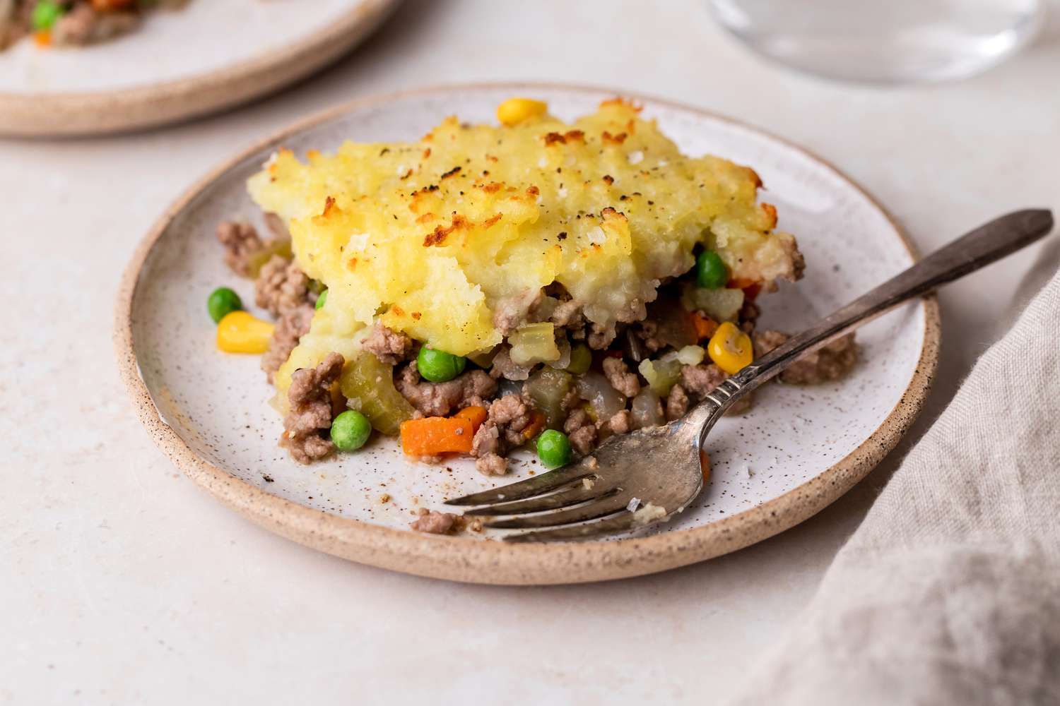 A slice of shepherd's pie on a plate with a fork.