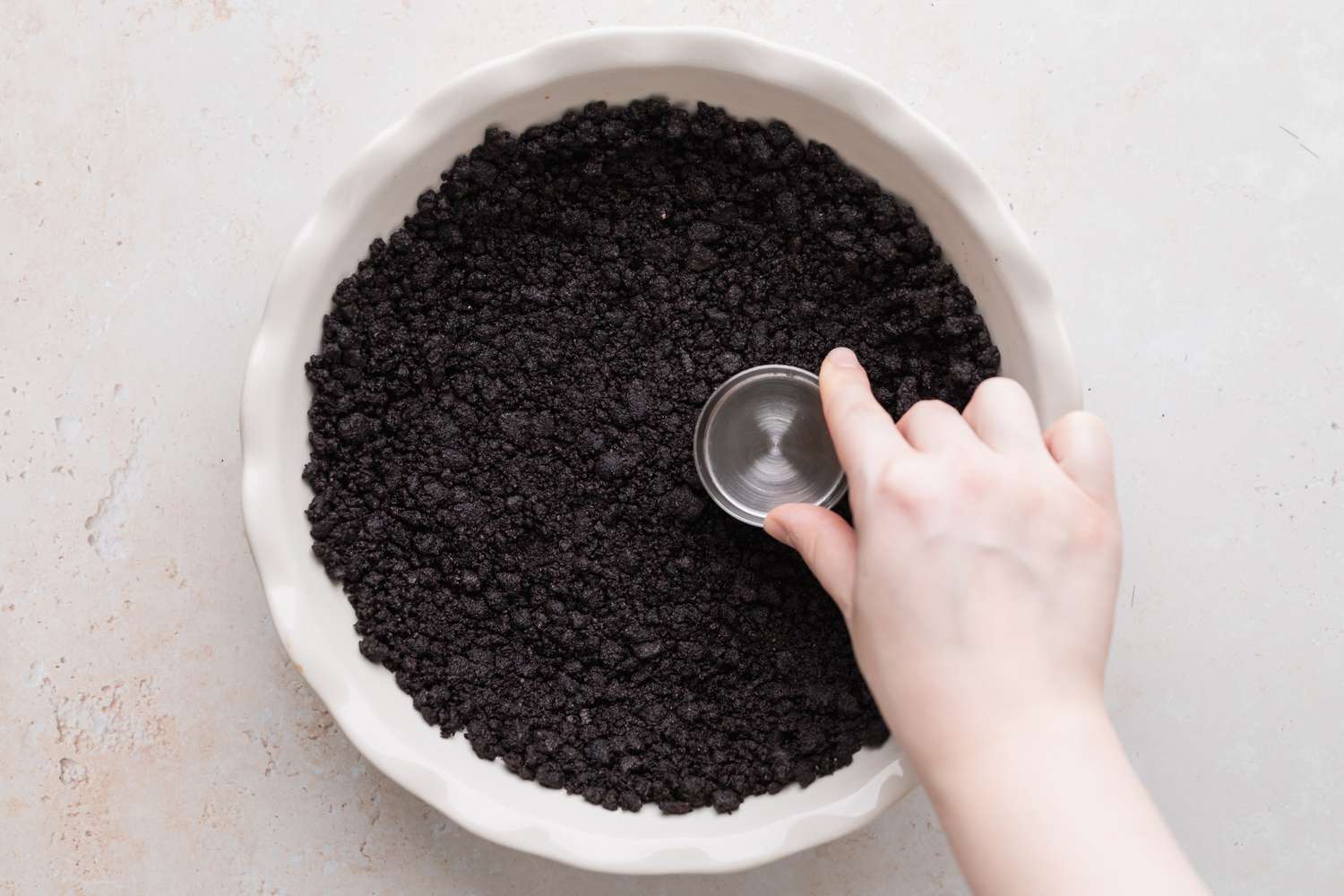 Overhead view of a ceramic pie plate with a chocolate cookie crust to make a grasshopper pie recipe.