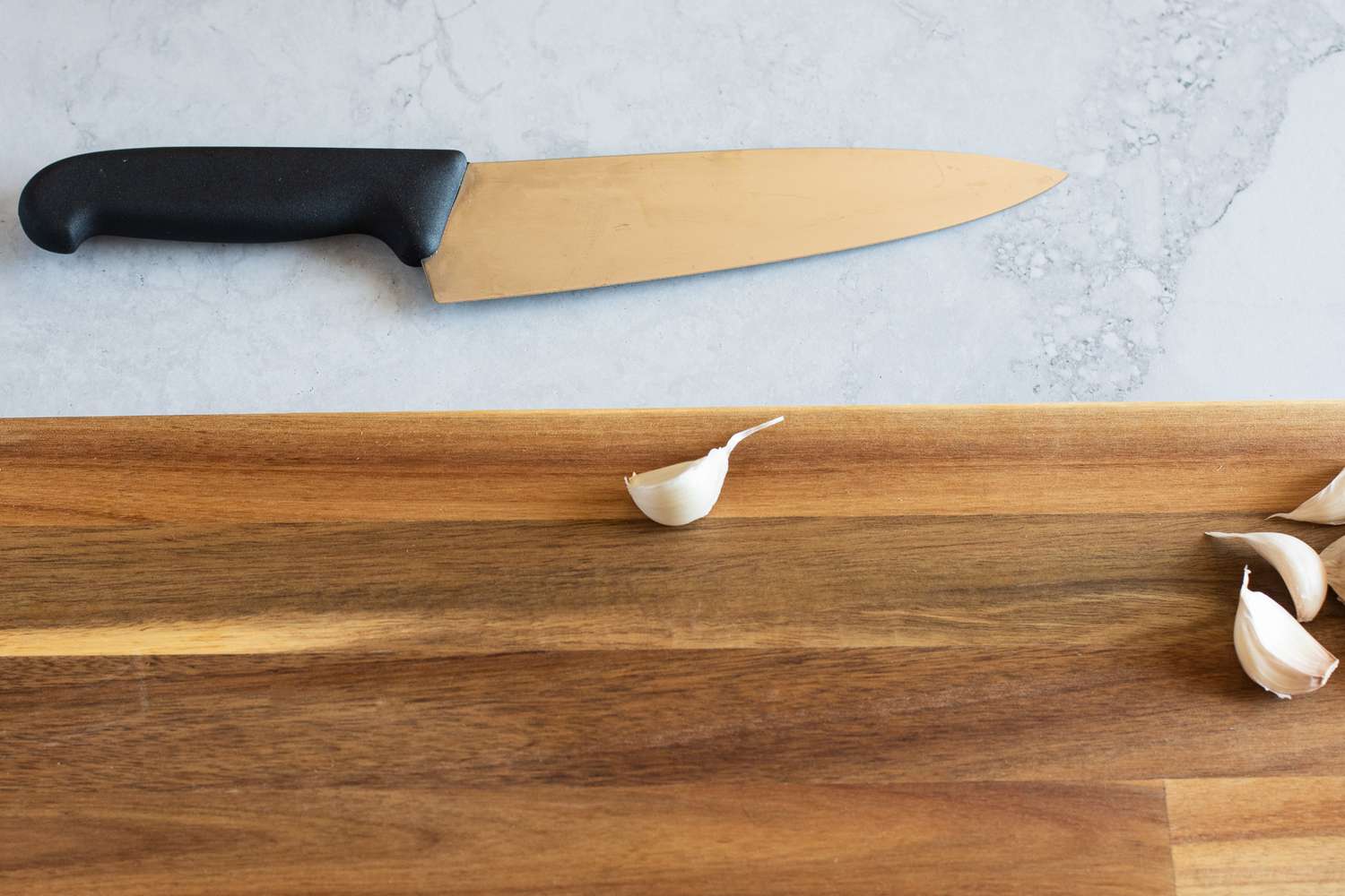 Single garlic clove next to a chef's knife