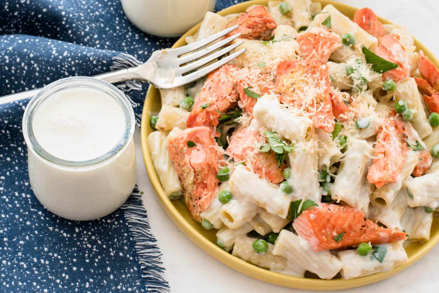 a bowl of salmon and pea pasta served with milk