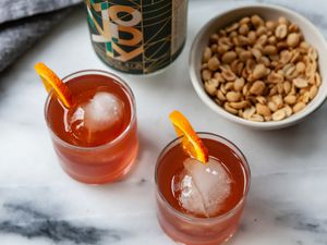 Overhead view of two Negronis with non alcoholic gin, bar nuts and an orange wedge.
