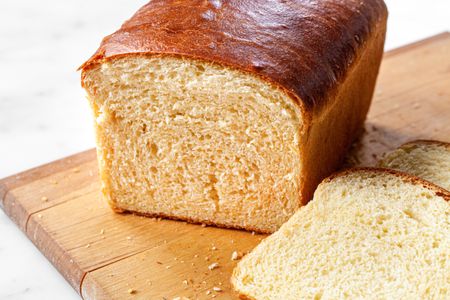 Brioche Sandwich Loaf on a Cutting Board with Slices of Bread Cascading Off the Board onto the Counter