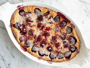 Cherry Clafouti Dusted With Powdered Sugar in a White Baking Dish