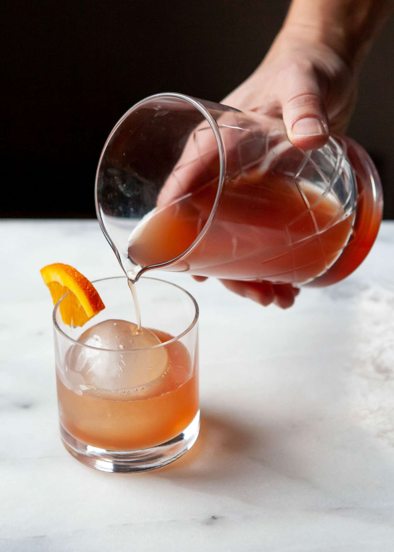 A person pouring an alcohol free negroni into a rocks glass.