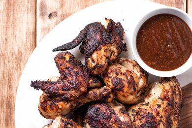 Overhead view of jerk chicken on a platter with dipping sauce.