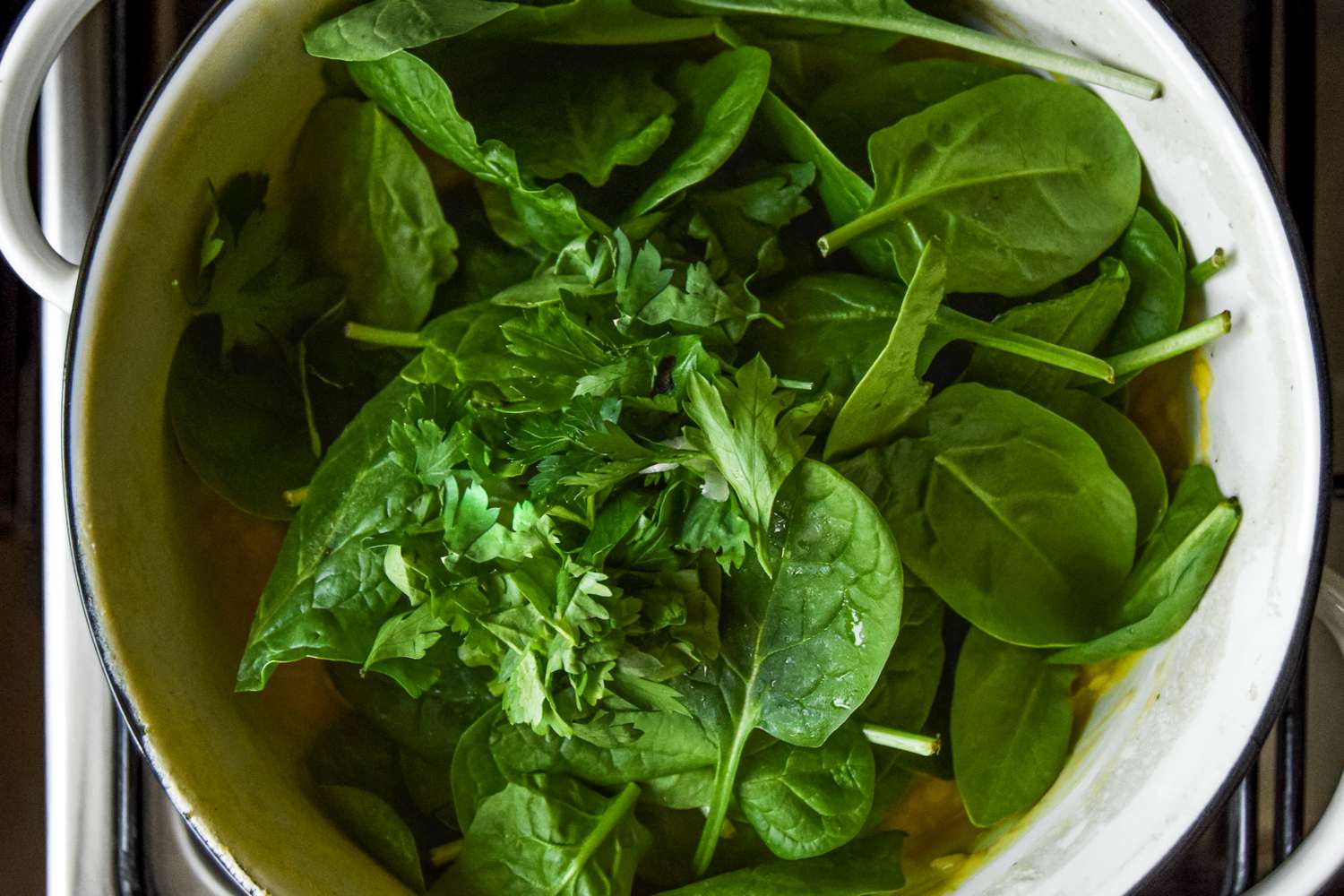 Spinach and Parsley Added to Daal Palak in Dutch Oven