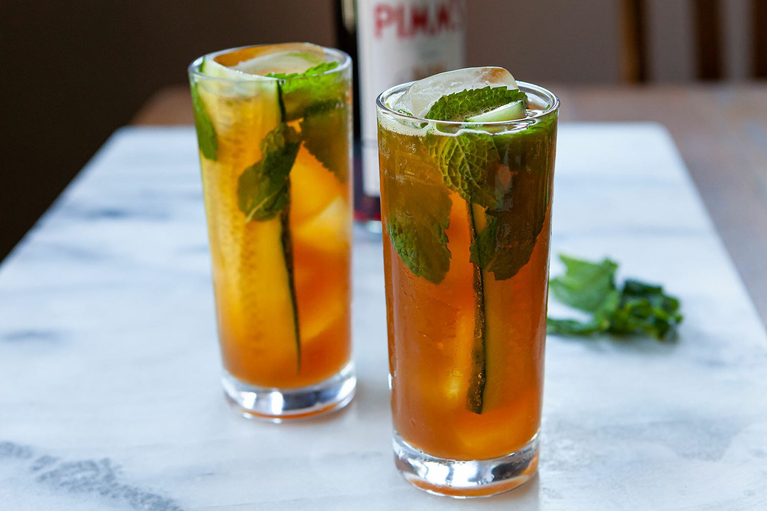 Two tall glasses of Pimm's Cup cocktails with fresh herbs