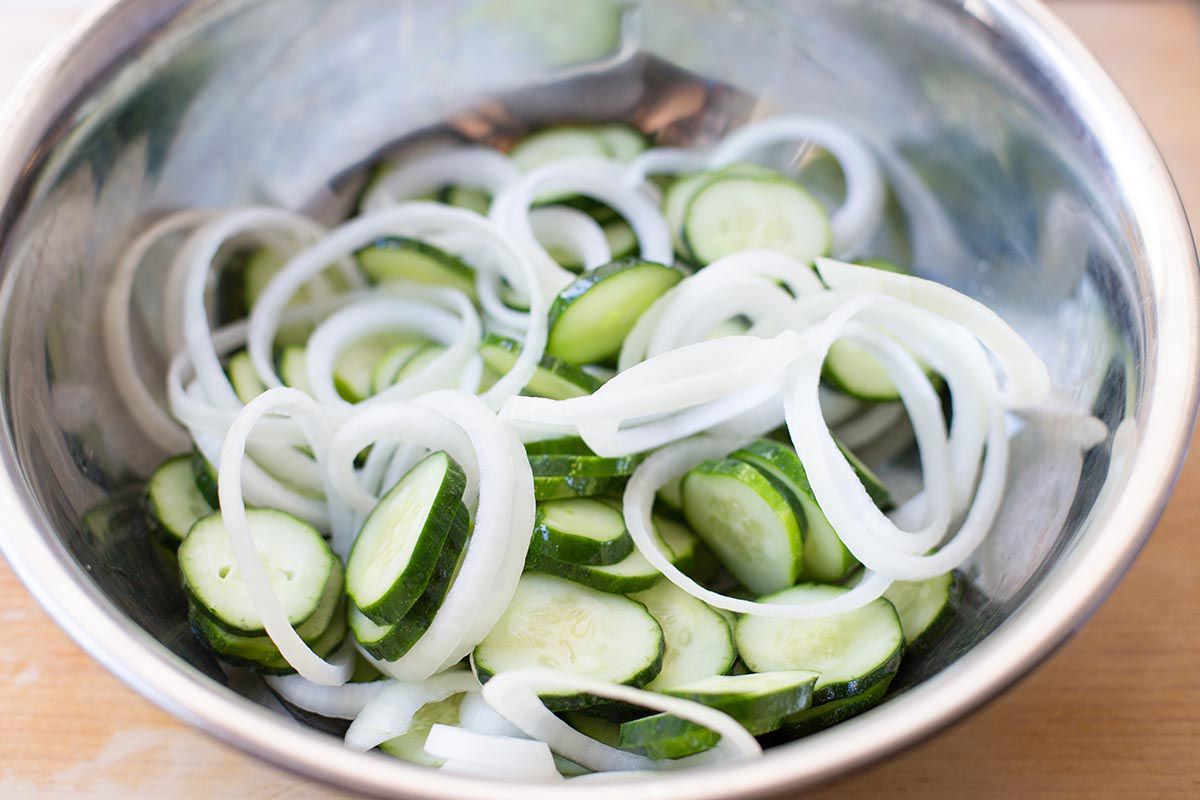 combine the sliced cucumbers with onions and pickling spices for making homemade pickles