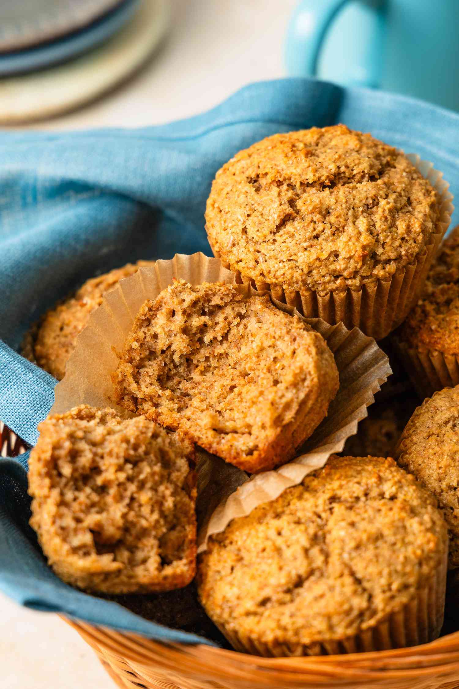 Bran muffins (one broken in half) in a table napkin lined basket