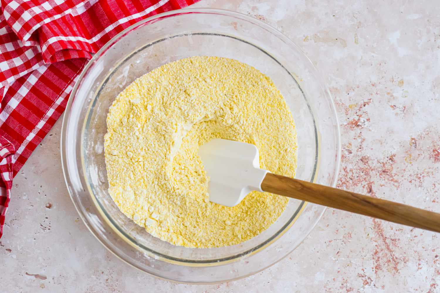Dry Ingredients Mixed Together Using a Rubber Spatula, and Next to It, the Kitchen Towel for Corn Dog Muffin Recipe