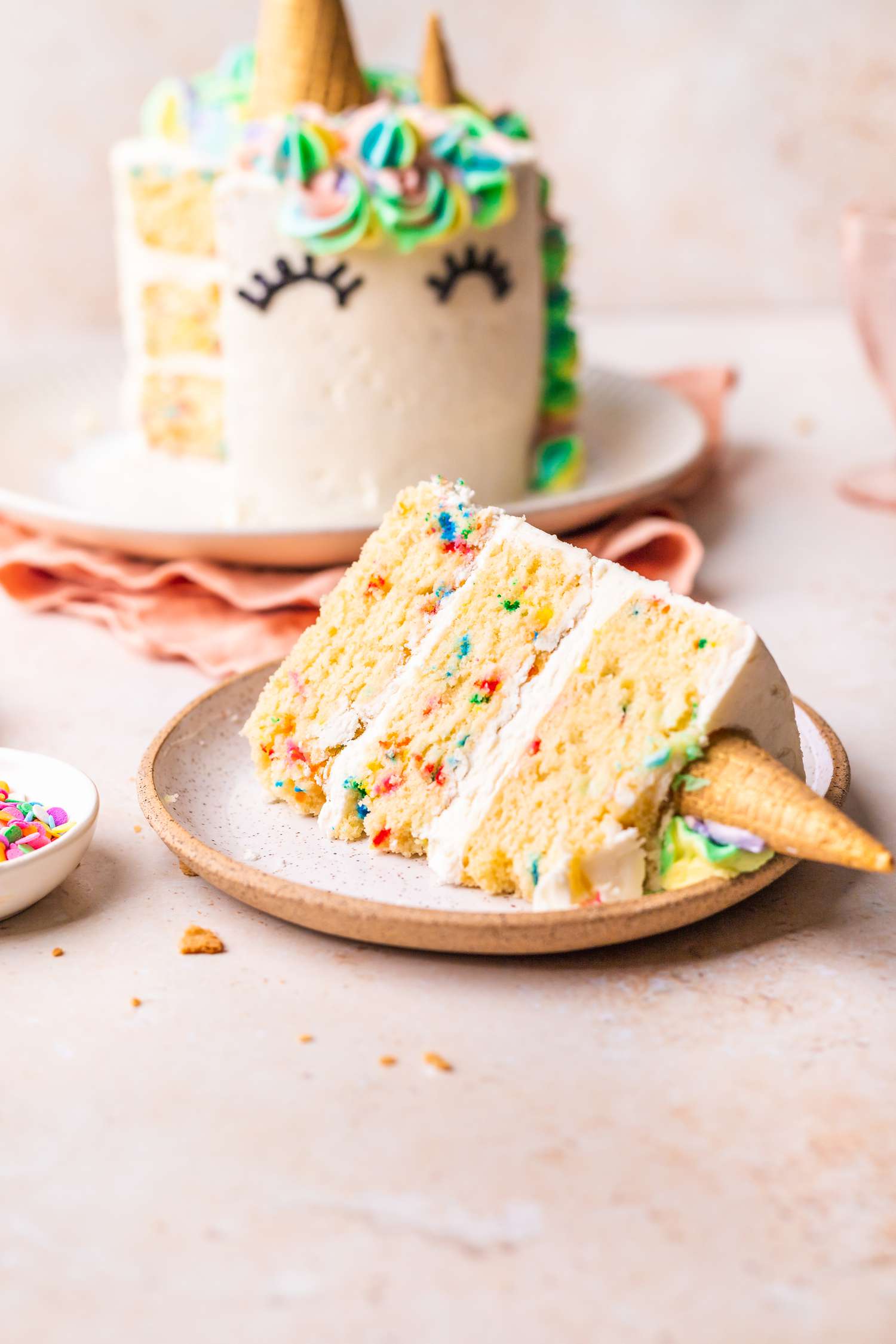 A Slice of Unicorn Cake on a Plate with the Rest of the Cake in Background