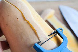 Vegetable peeler peeling a butternut squash