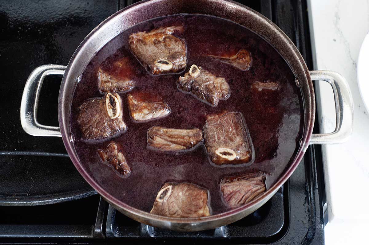 Short ribs recipe cooking on a stove.