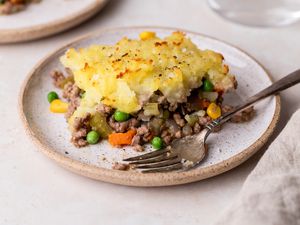 A piece of shepherds pie on a plate with a fork.