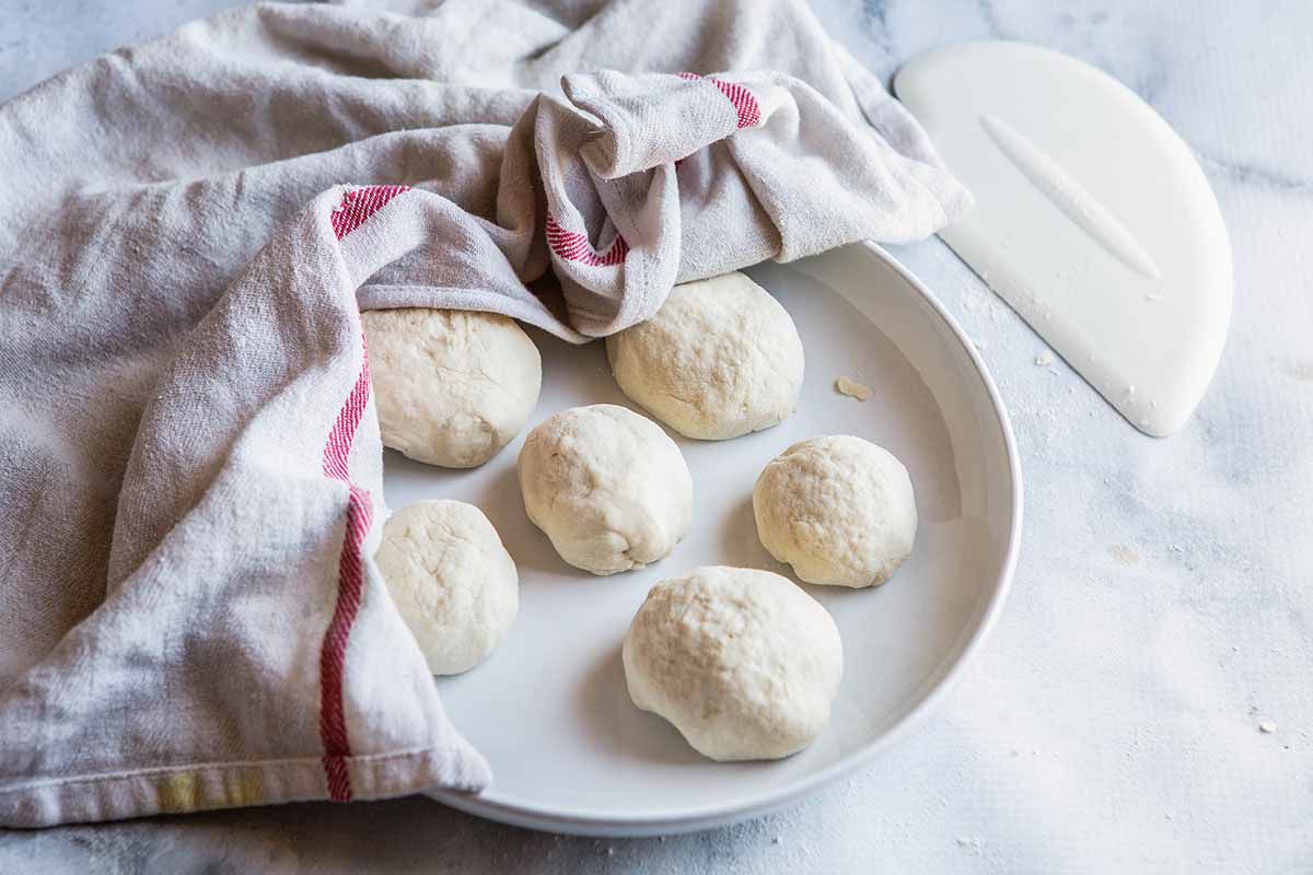 Easy Naan Recipe - dough balls on plate covered with towel