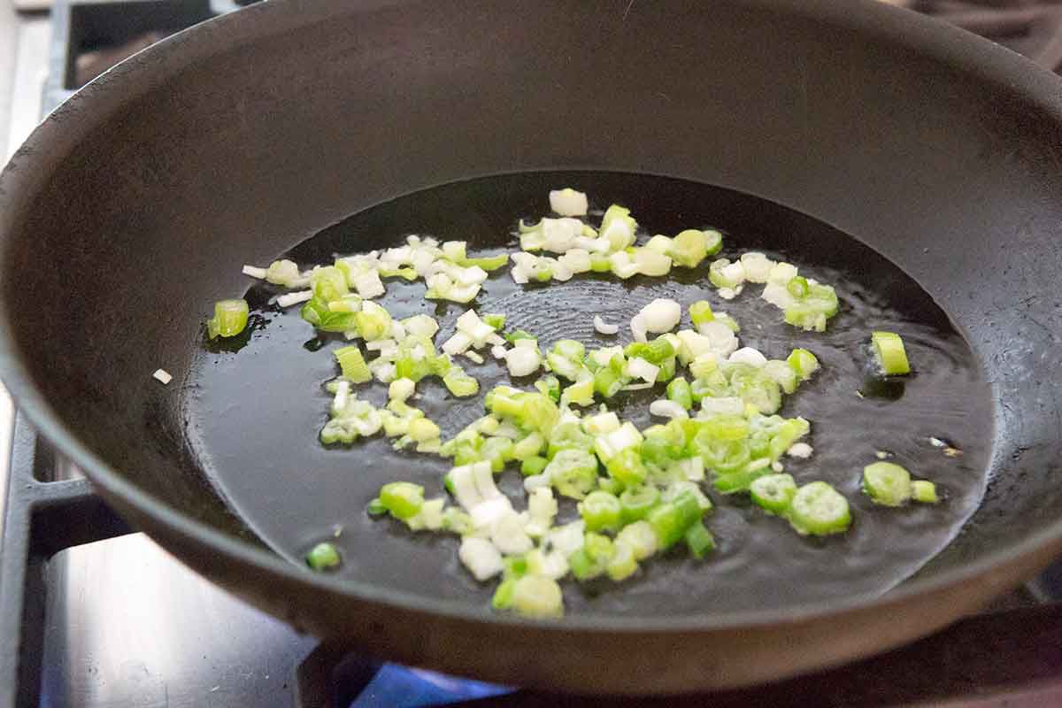 chopped green onions sautéing on a pan 