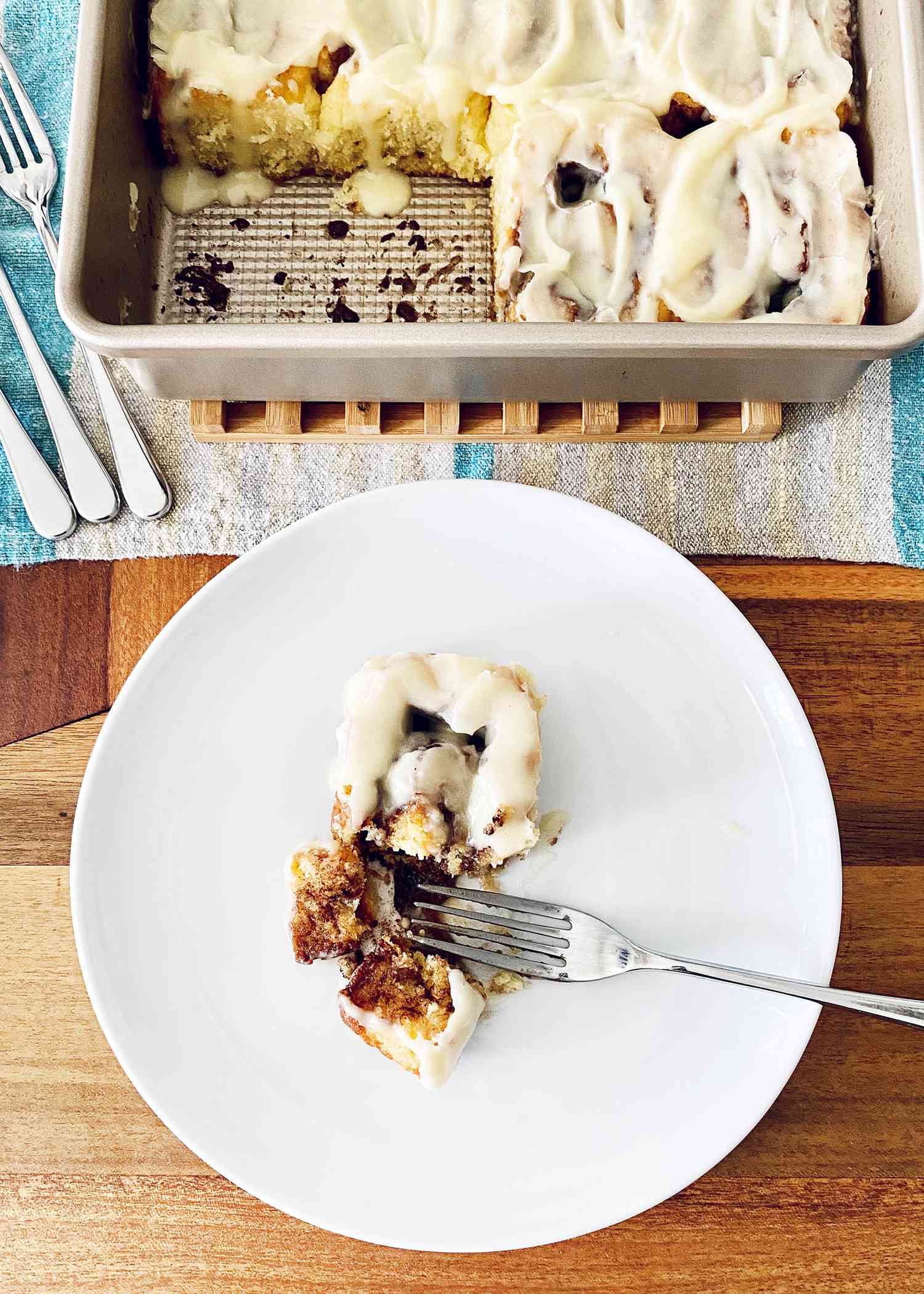 A plate with the best gluten free cinnamon rolls and a pan of the rest of the frosted rolls behind the plate.