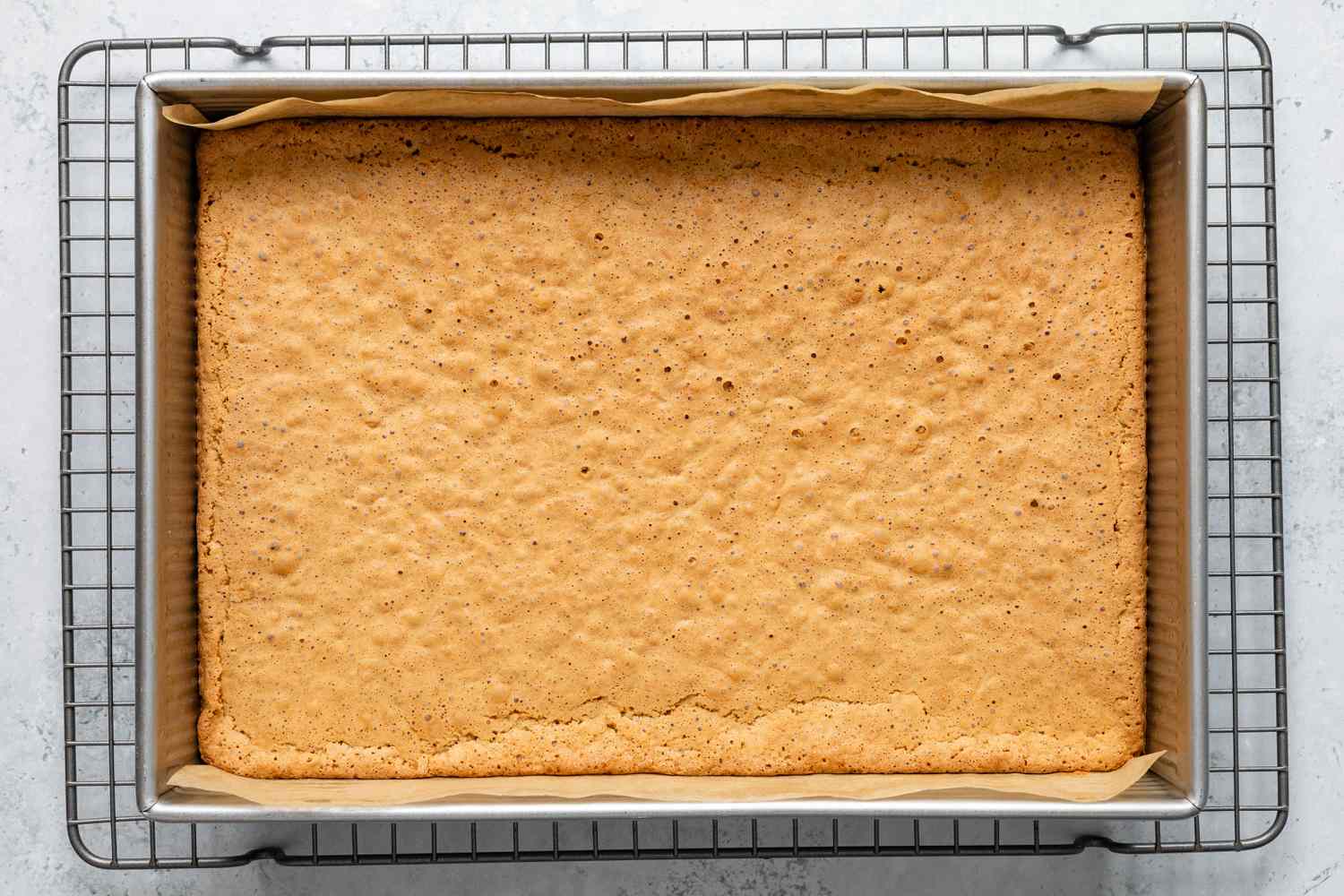 Baked Sad Cake in a Parchment Paper Lined Baking Sheet Sitting on a Cooling Rack