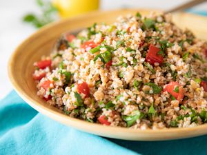 Side view of a tabbouleh salad in a tan bowl.