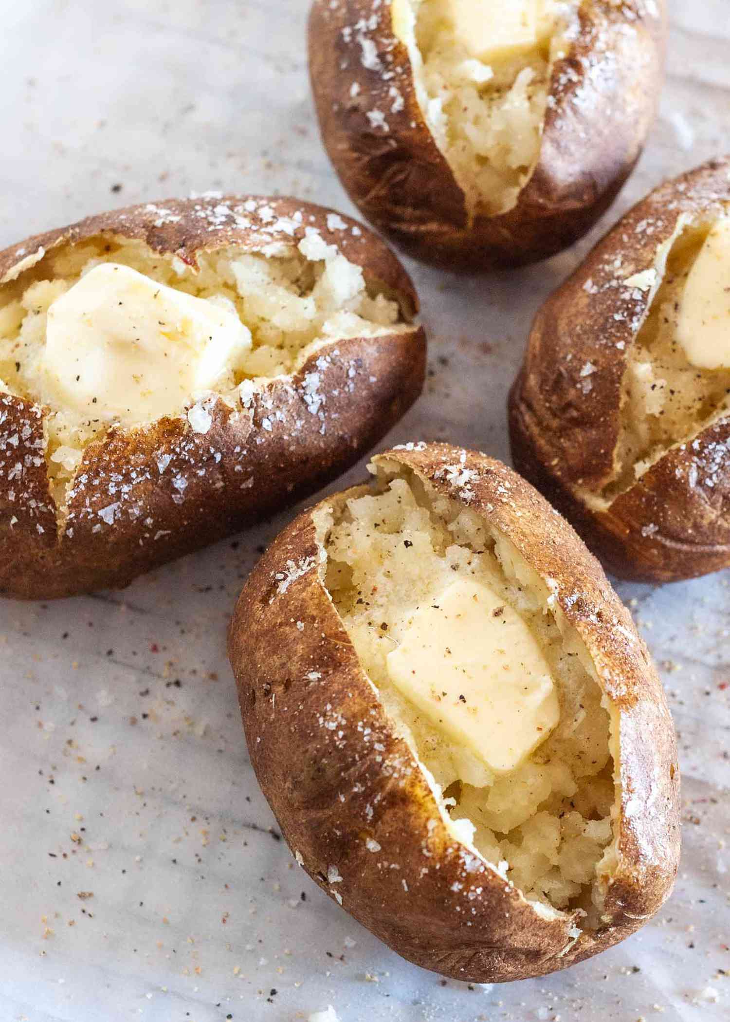 Four potatoes split open with butter and salt on the inside
