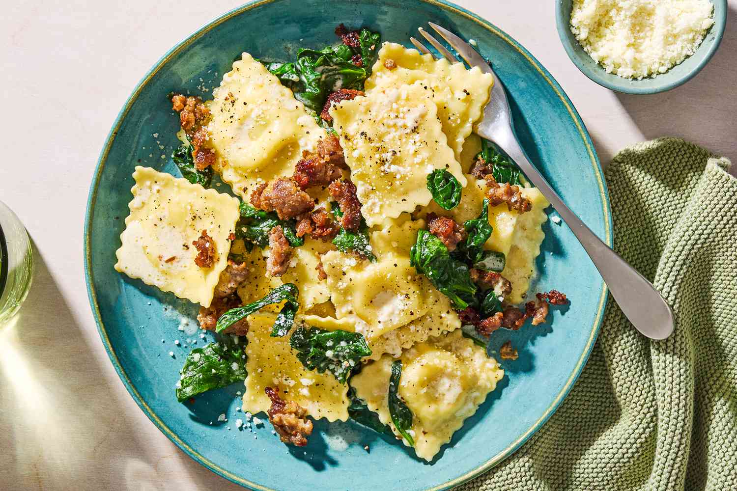 Overhead view of 15-minute one pan ravioli topped with Parmesan cheese in a light blue bowl with a fork