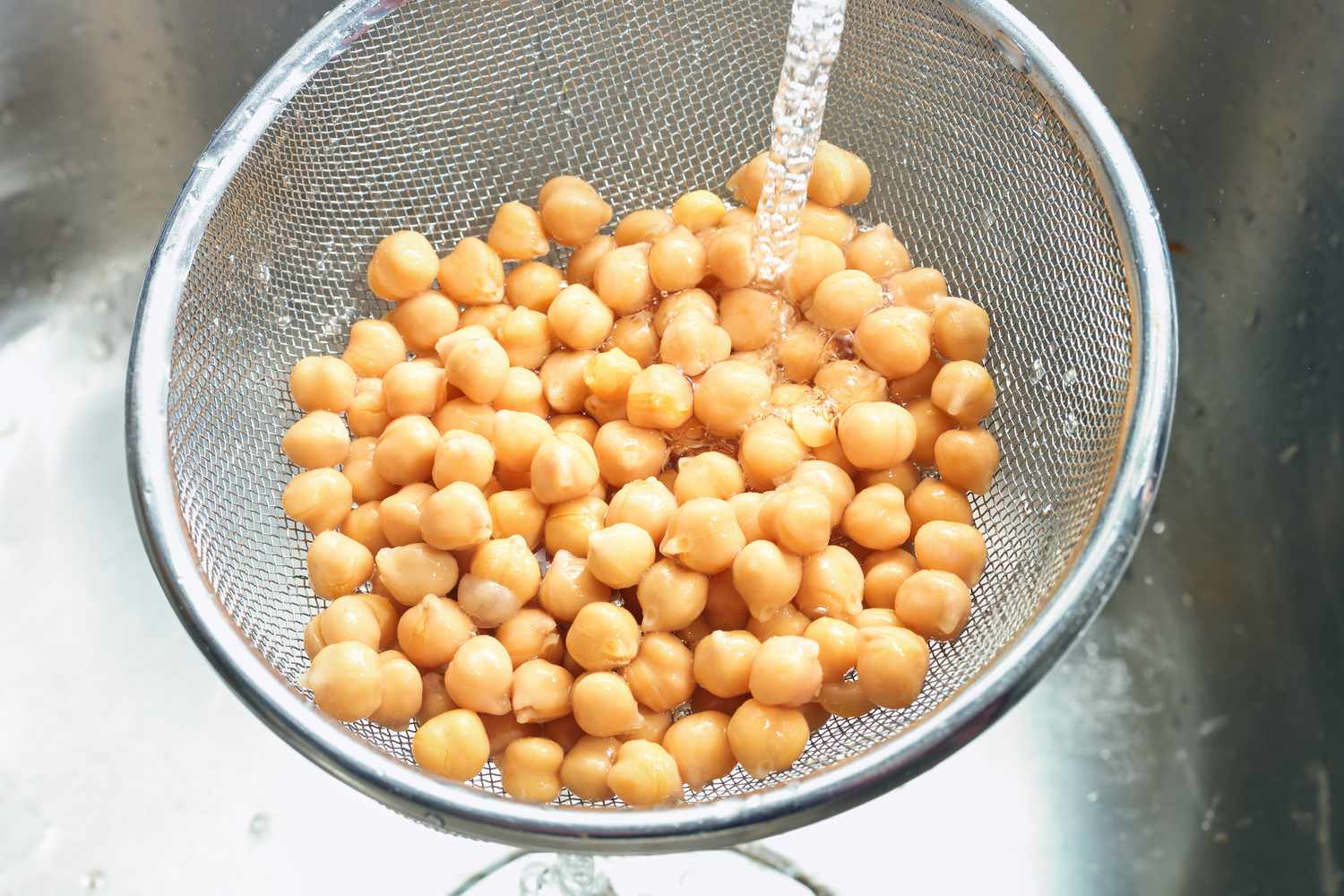 Chickpeas in a colander under running water