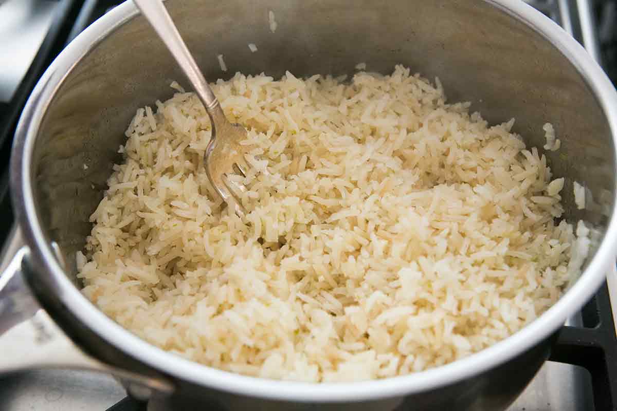 Cooked riced in a pot with a fork fluffing the rice