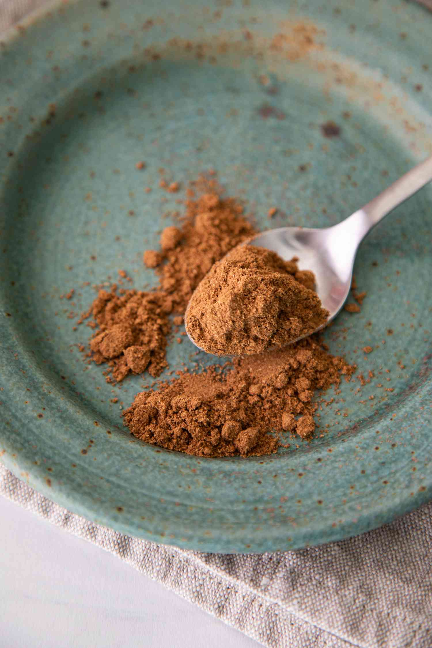 Chinese Five Spice on a Spoon with Some Overflowing onto a Plate