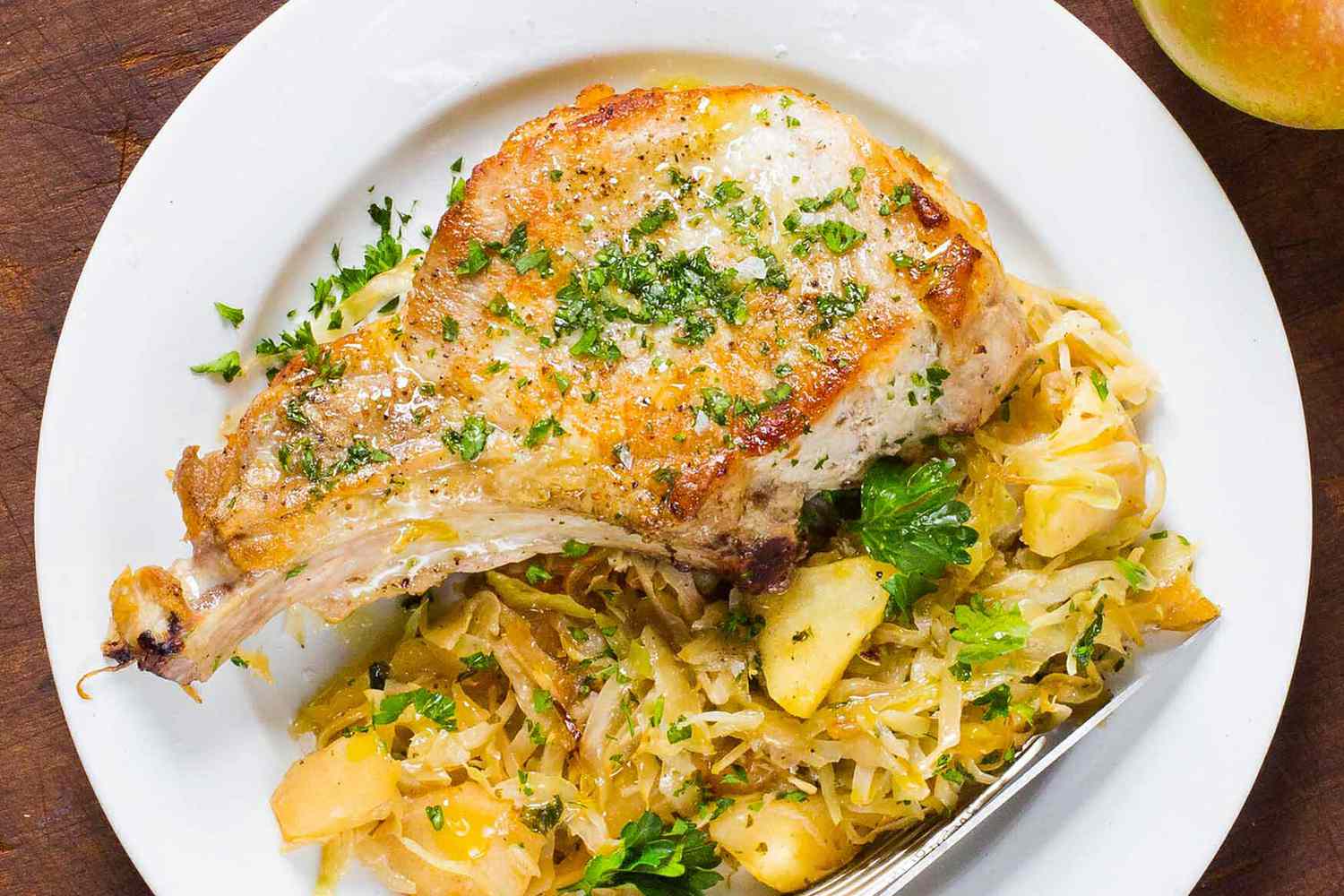 pork chop with apples and cabbage on a white plate