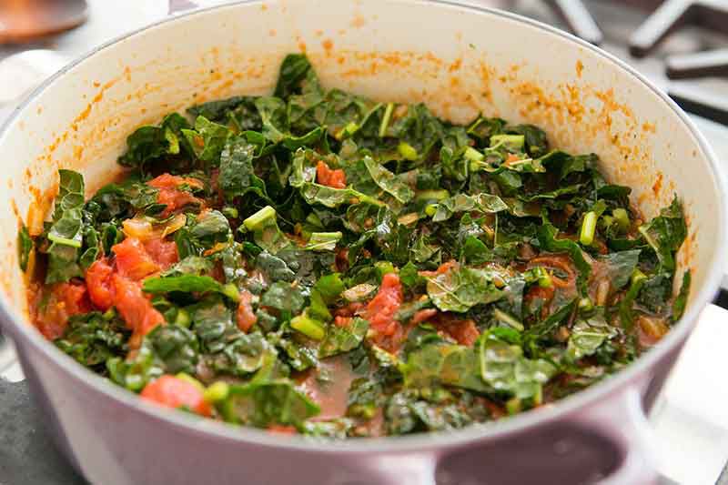 healthy pot of roasted root vegetables, tomatoes, kale