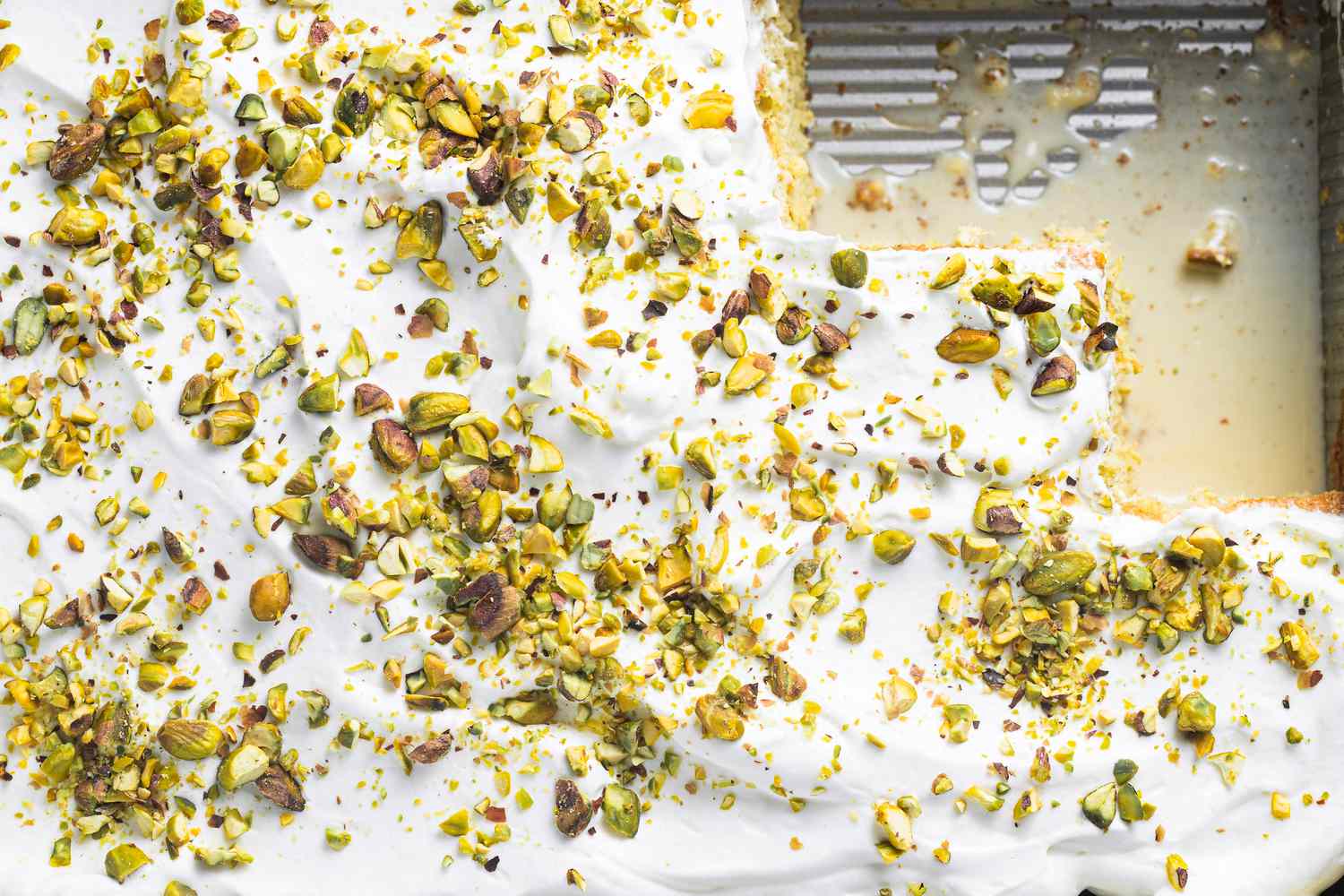 Tray of Tres Leches with Pistachio and Cardamom with Some Pieces Cut Out
