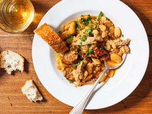 Bowl of cassoulet with bread and white wine.