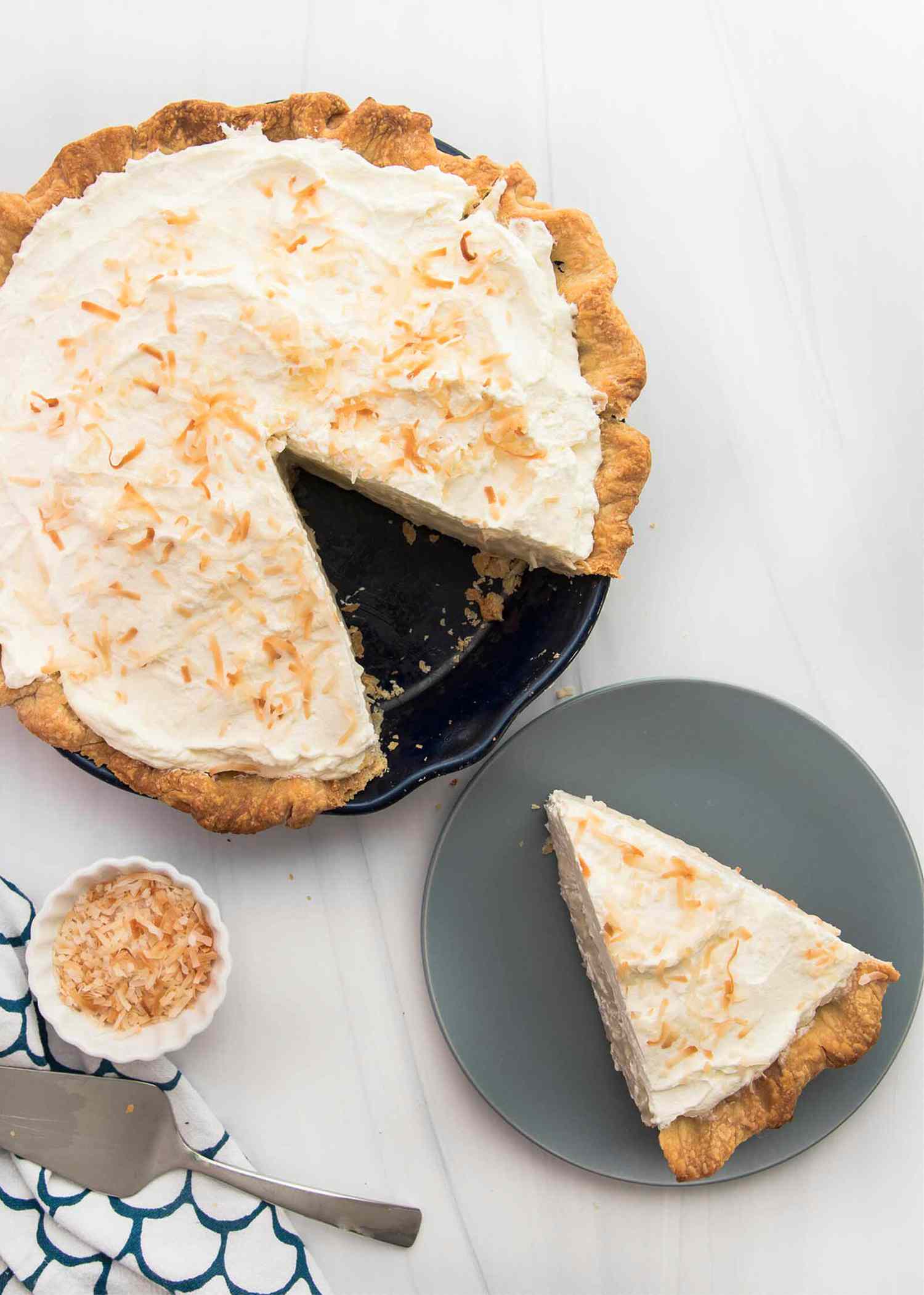 Overhead view of the best coconut cream pie with a slice removed and set on a plate.