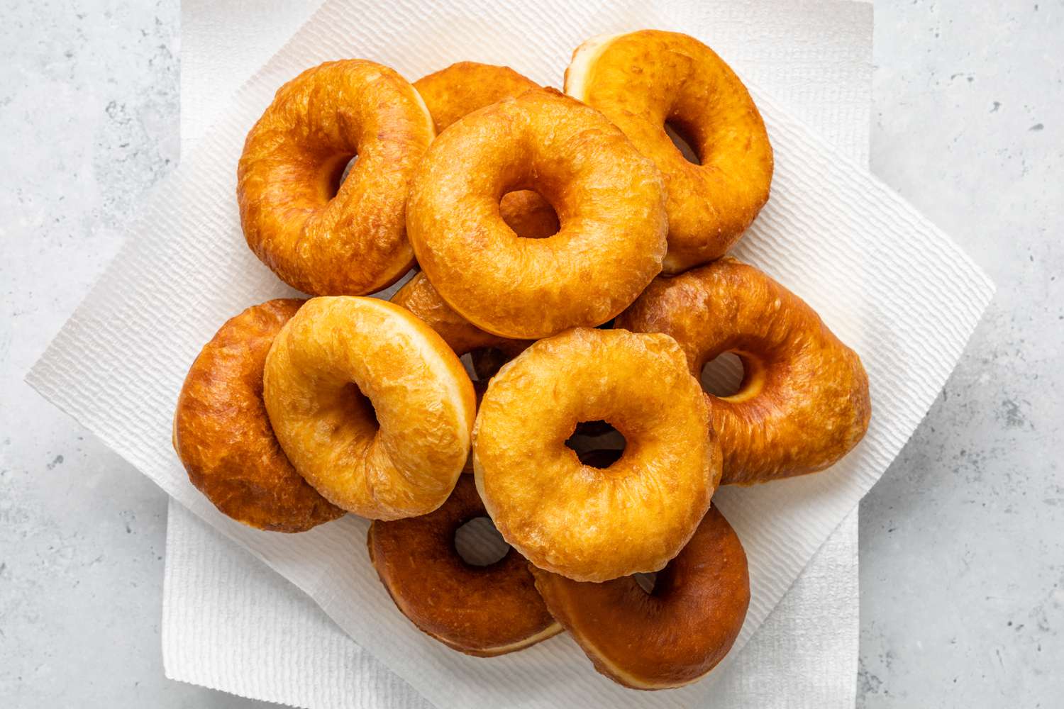 Pile of Doughnuts Resting on a Paper Towel Lined Plate 