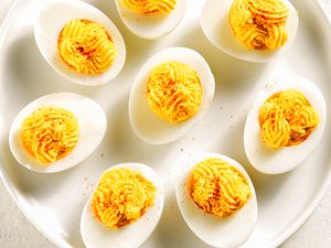 Deviled eggs arranged on a white plate, topped with a sprinkle of seasoning.