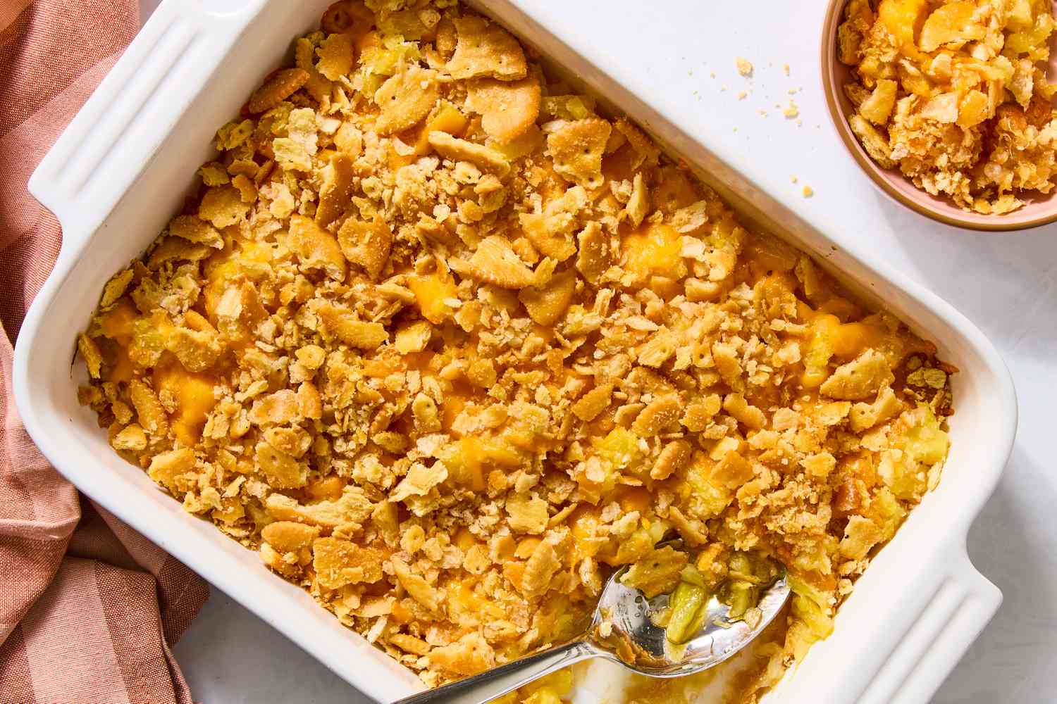 overhead view of Pineapple Casserole in a dish with a spoon, small bowl of it on the side