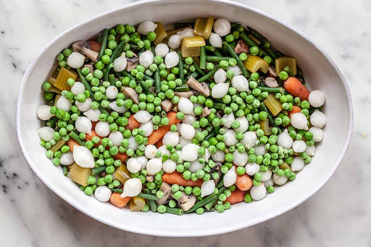 Vegetarian Shepherd’s Pie Recipe -- white casserole dish filled with carrots, peas, onions, mushrooms
