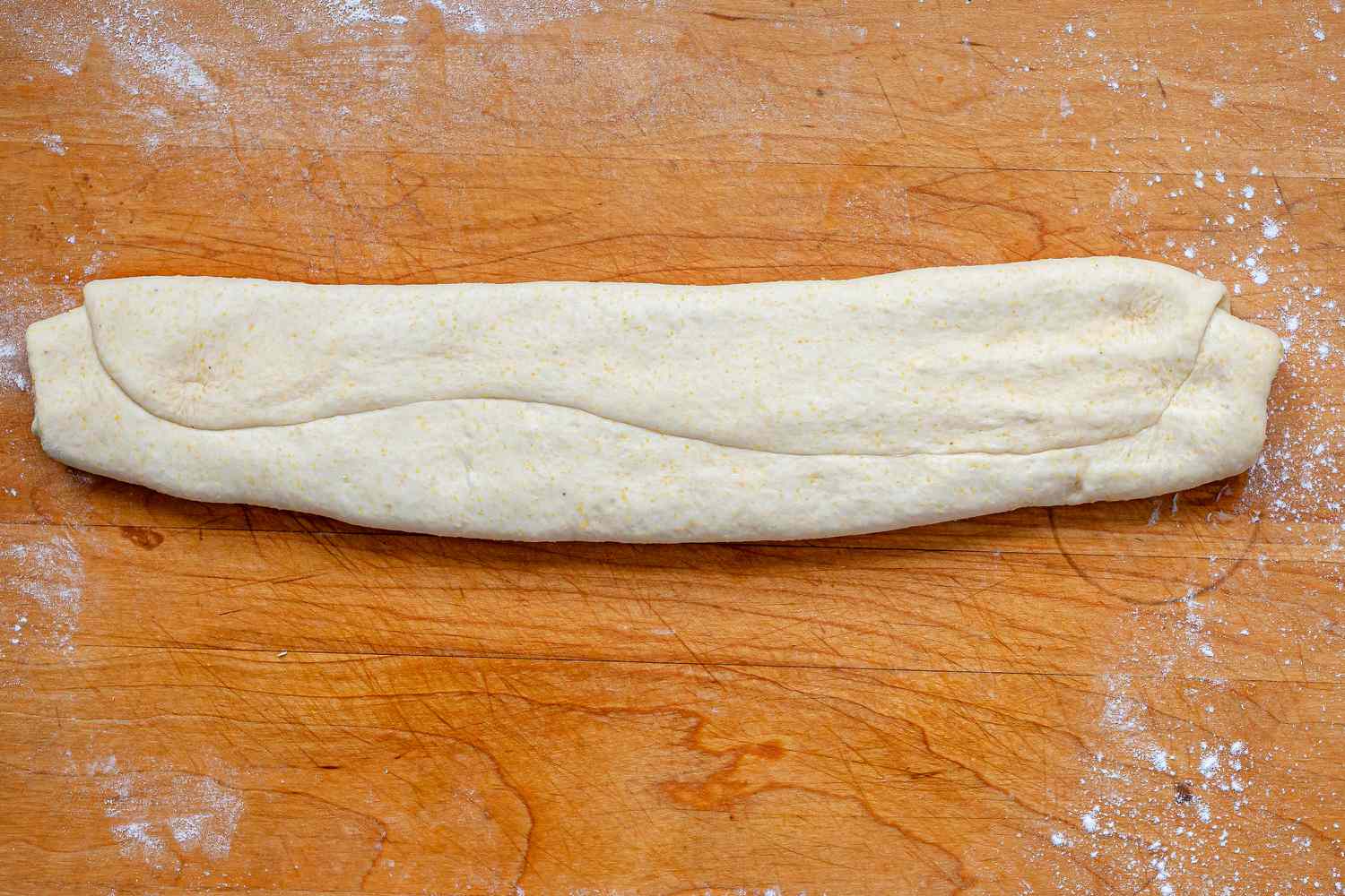 Dough to make Italian Sausage Deep Dish Pizza on a cutting board.