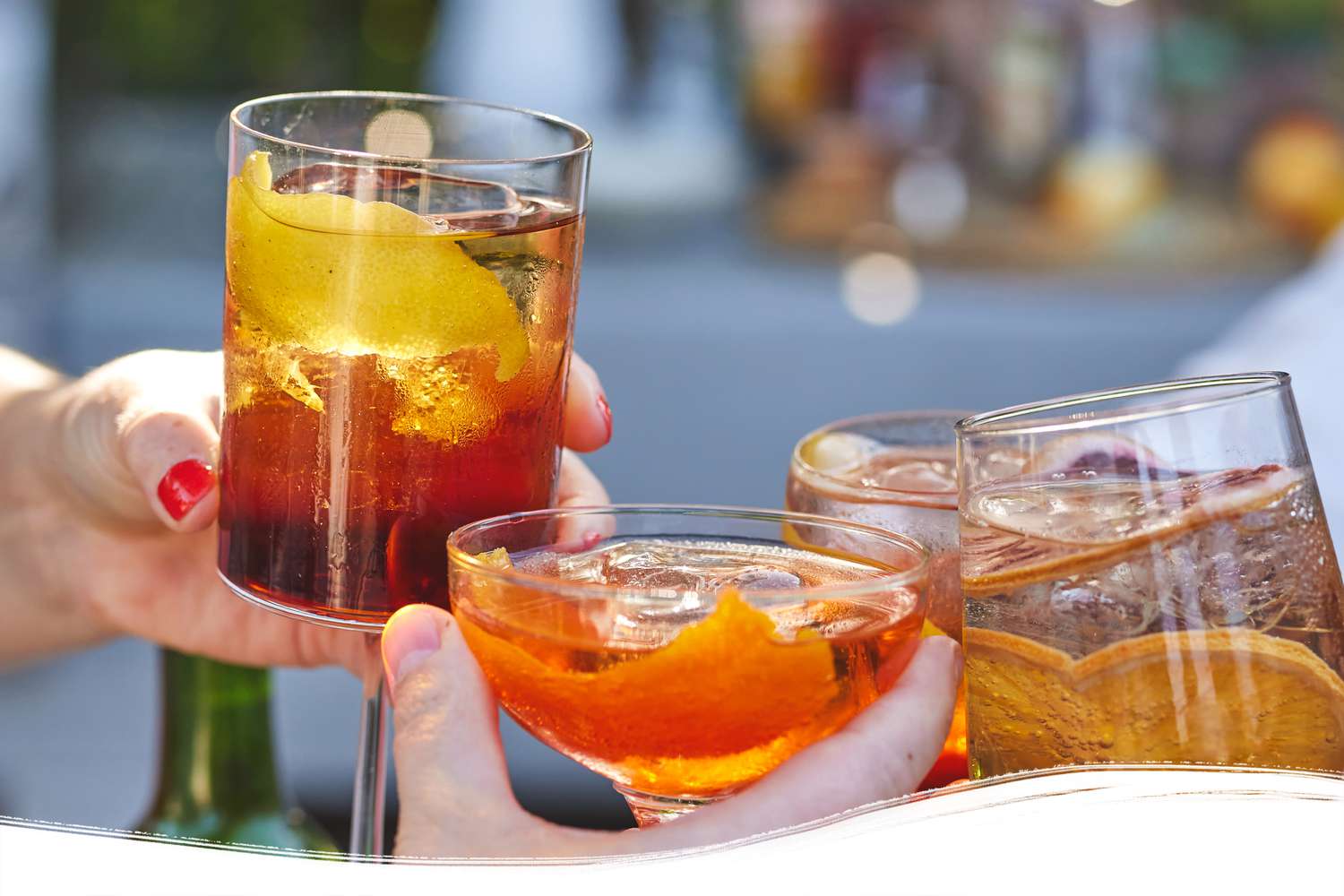 Glasses clinking with colorful drinks in backyard