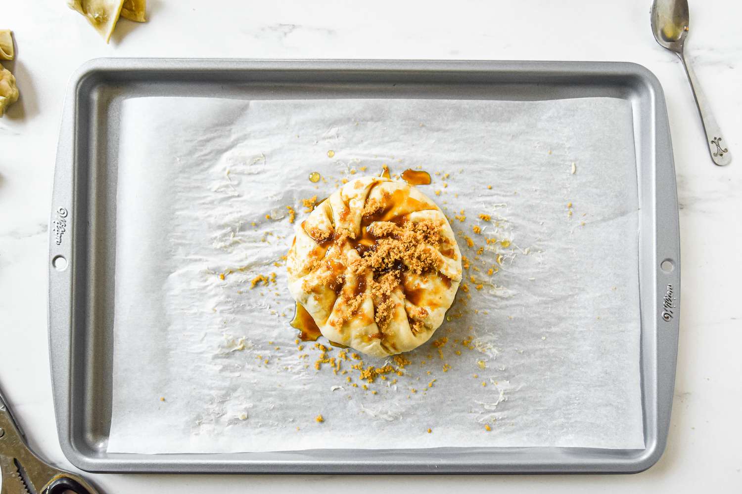 Overhead view of a baking sheet with brie wrapped in puff pastry for a baked brie recipe