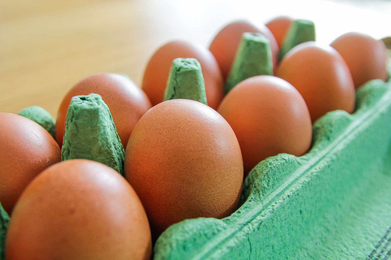 An open carton of brown eggs on the counter