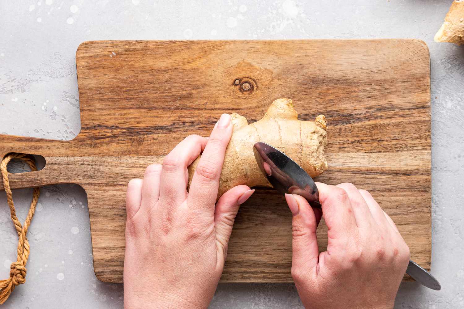 Hands Holding a Piece of Ginger and a Spoon