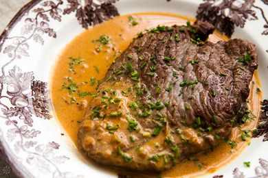 A Steak Diane resting in a sauce on a plate