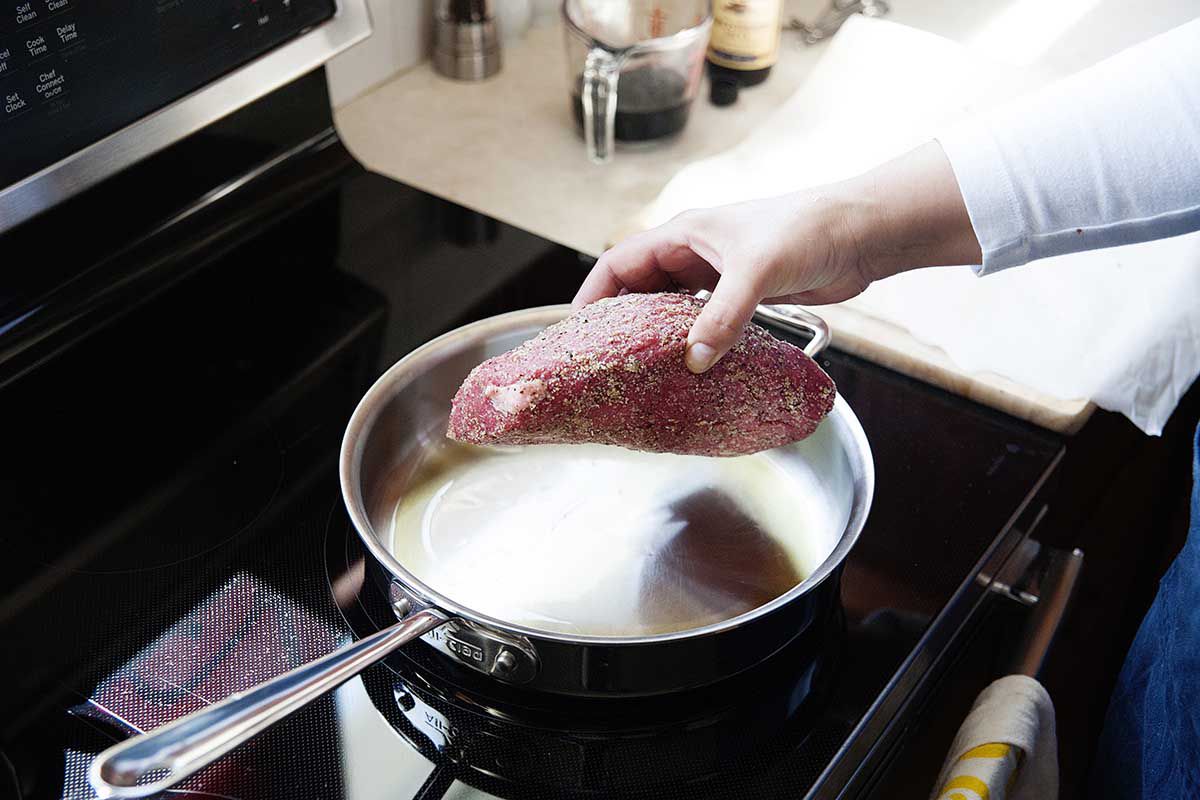 Placing a roast into a hot skillet.