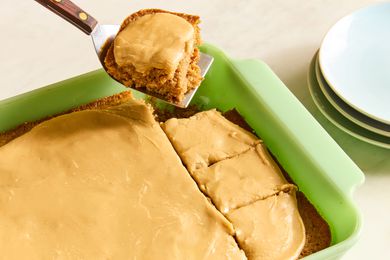 baking dish with Grandma’s Oatmeal Cake, slices cut and one slice on a metal spatula with plates for serving
