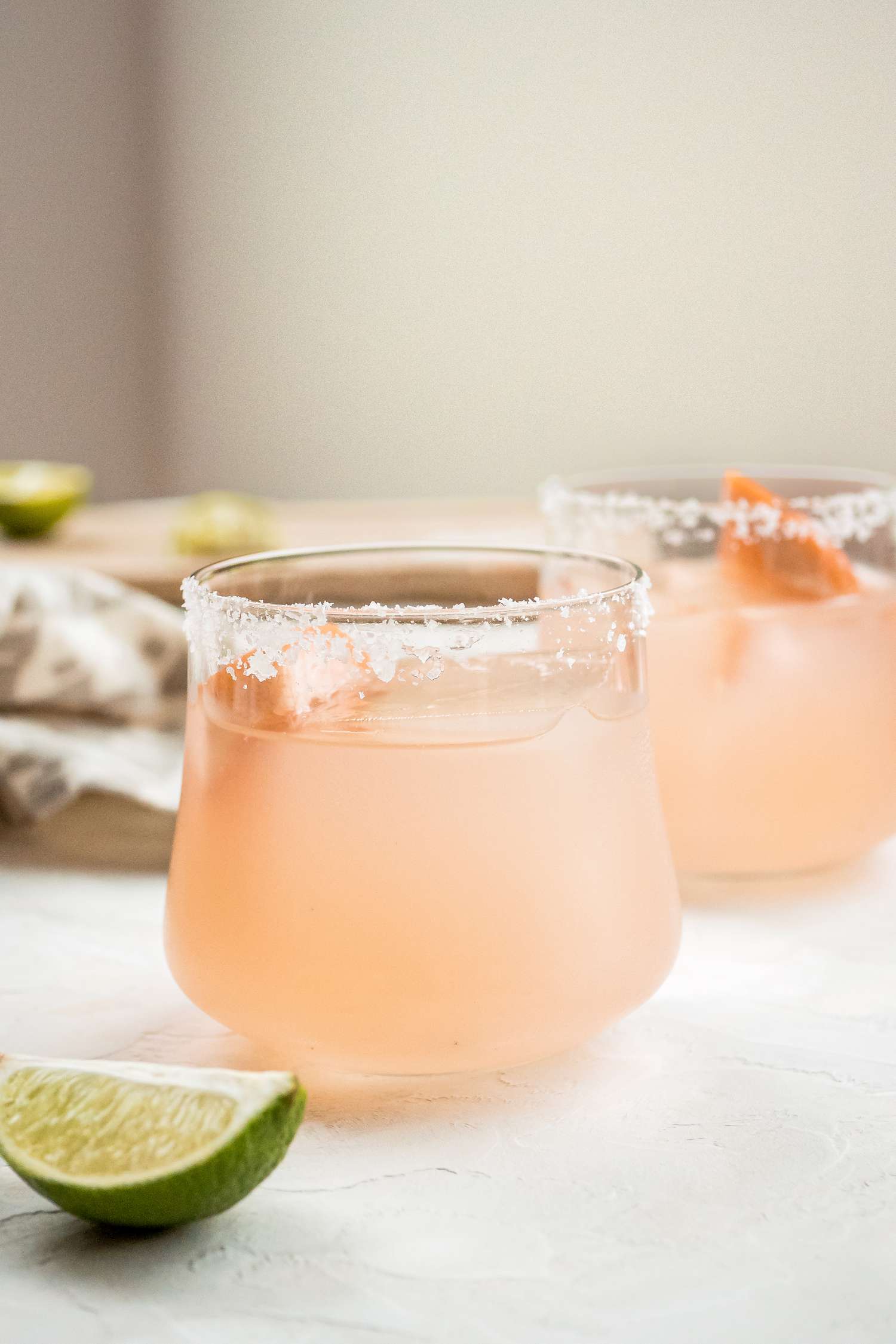 Two delicious grapefruit margaritas garnished with a grapefruit wedge.