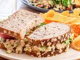 Side view of chickpea salad sandwich on a plate with chips.